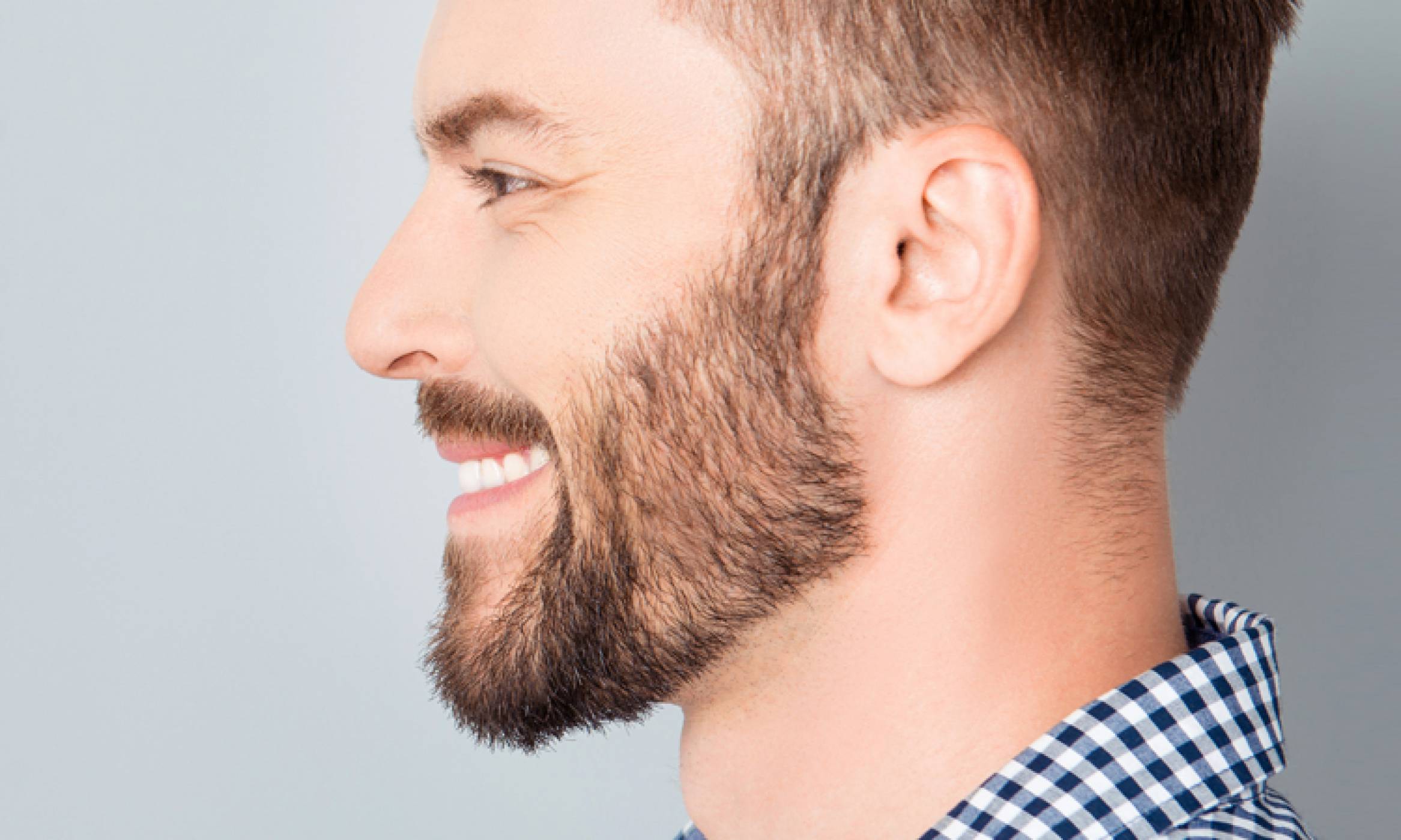 A man with a full beard, thick lashes, & natural-looking brows, showcasing the results of a successful hair transplant