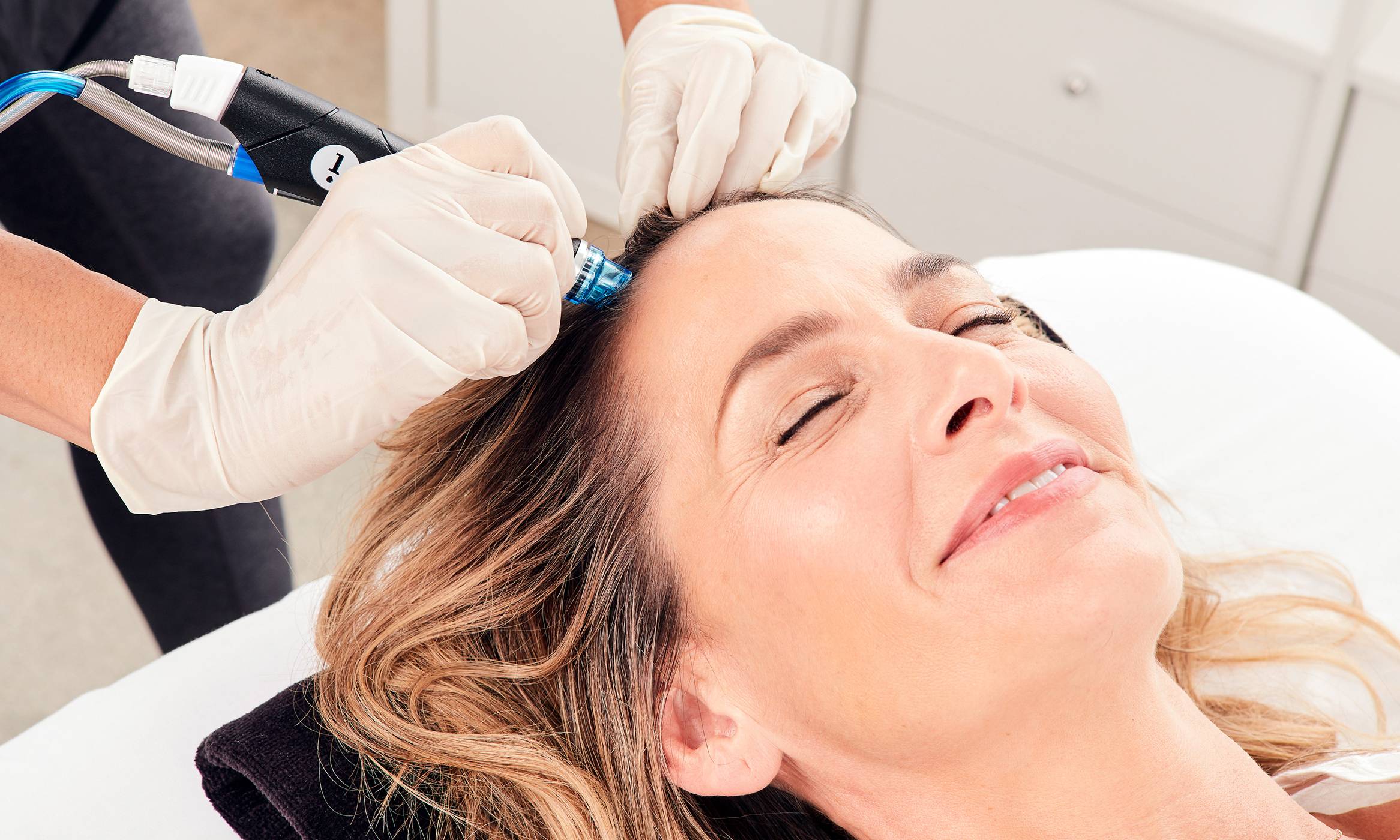 Close-up of relaxed man with eyes closed undergoing HydraFacial Keravive treatment for hair loss to help regrow thicker hair.