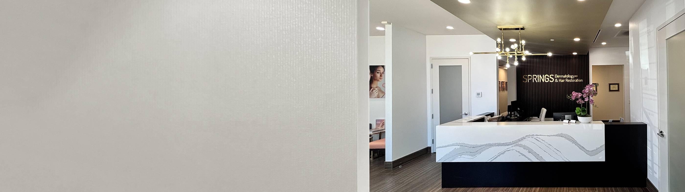 A friendly front desk welcomes patients in the modern, well-lit, and comfortable lobby of the Springs Hair Restoration.