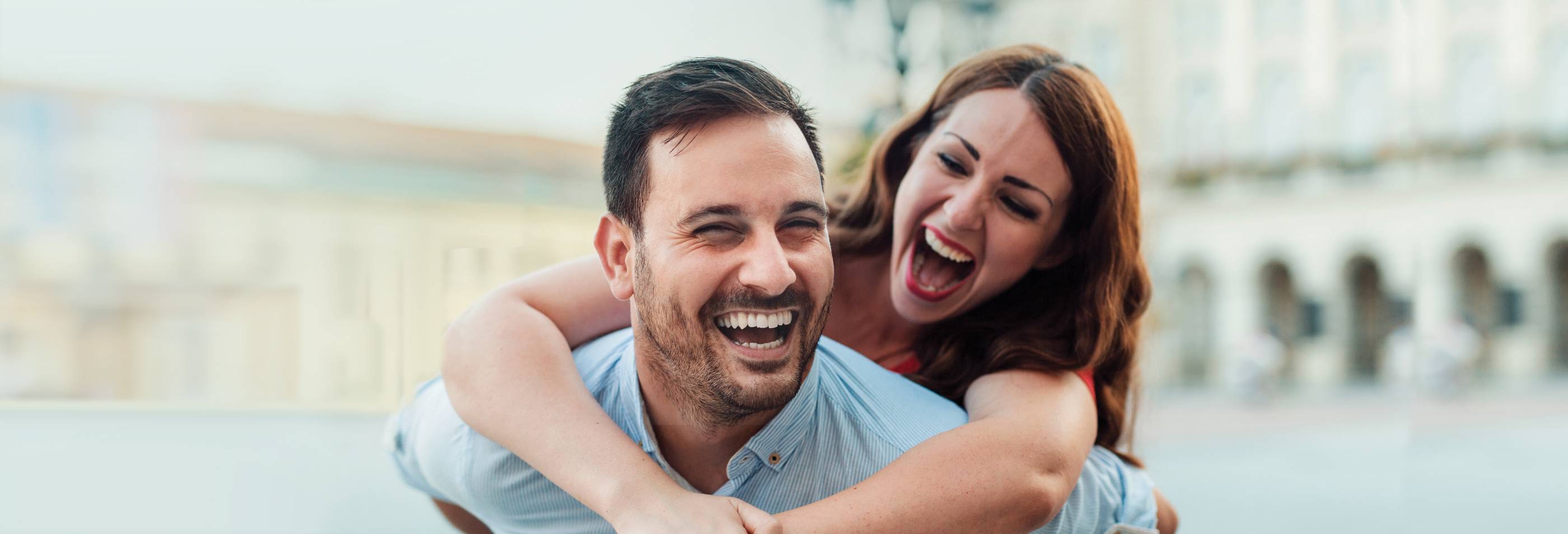 Cheerful couple with the woman hugging him and admiring his full head of short hair. Successful hair restoration.