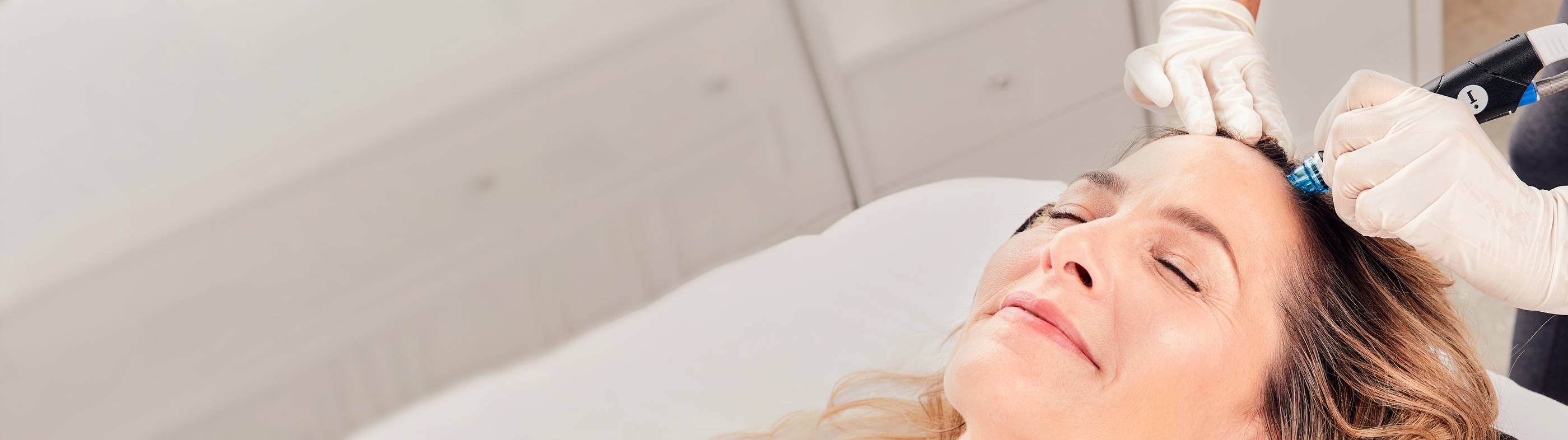 Close-up of relaxed man with eyes closed undergoing HydraFacial Keravive treatment for hair loss to help regrow thicker hair.